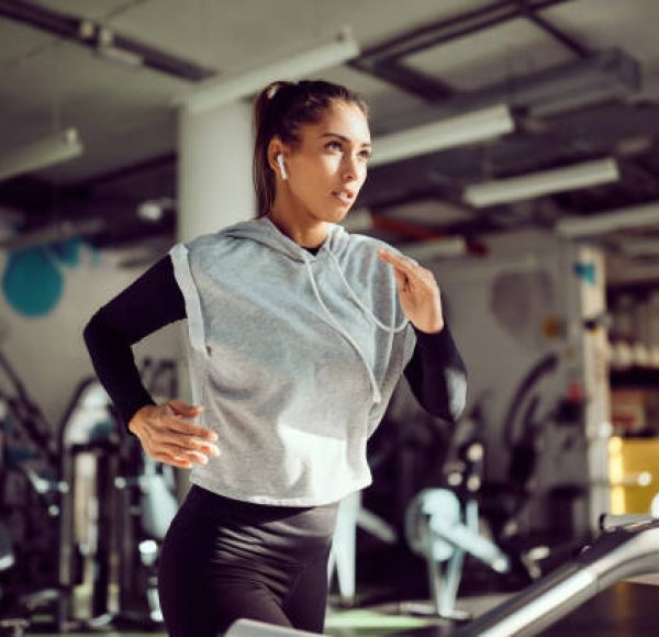 Young female runner exercising on treadmill in a gym.